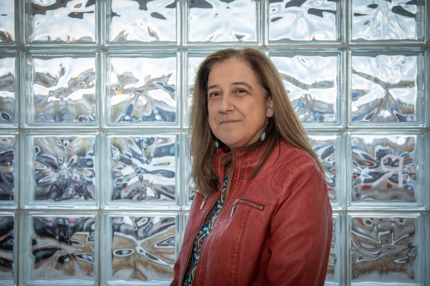 Inmaculada Alva Rodríguez posando frente a una cristalera de la Casa de la Cultura de Burlada antes de comenzar la conferencia. Fotografía: Maite H.Mateo.